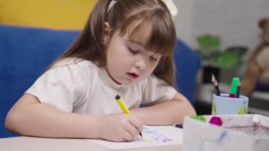 Küçük bir çocuk albümde keçeli kalemle resim çizer, resim dersleri alır, çocuk odasında bir sanatçıyı oynar, çocukluk hayali güzel bir şekilde resim yapmayı öğrenir, kız renk çizer.