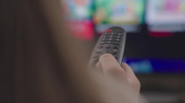 Uzaktan kumanda ile uzaktan kumandayı parmak, akşam haberleri, TV programları, koltukta dinlenme, ekipmanları uzaktan kontrol etmek için modern teknoloji, monitör ekranı bir uygulamadır.