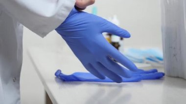 Hastane sağlık görevlisi ellerine tıbbi stiren eldivenler takar, koruyucu sağlık maskesi takar, hastanedeki hastaların sağlığını izler, beyaz önlüklü hemşire, sağlık araştırmaları, konsept eldiven modu.