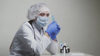 Tıp önlüğü ve steteskop takmış genç bir kadın. Yüzünde tıbbi maskeyle telefonda konuşan bir doktor. Klinikte terapist.