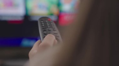 Uzaktan kumanda ile uzaktan kumandayı parmak, akşam haberleri, TV programları, koltukta dinlenme, ekipmanları uzaktan kontrol etmek için modern teknoloji, monitör ekranı bir uygulamadır.