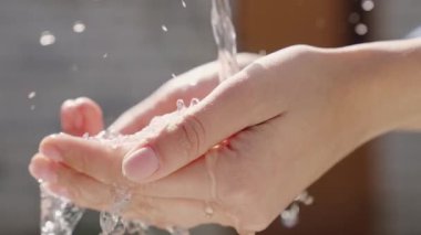 Ellere ıslak şeffaf temiz su akıntısı dökülür, temiz insan derisinin hijyenini gözlemler, parmakları nemlendirir ve yıkar, işten sonra temizler ve yıkar, kiri temizler, yakın plan temizler.