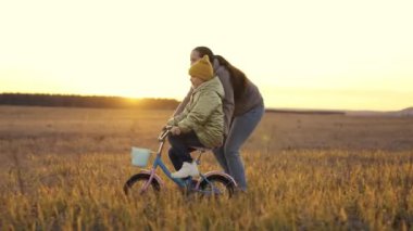 Küçük çocuk iki tekerlekli bisiklet sürmeyi öğreniyor. Annesi direksiyondaki çocukla bisikleti itiyor. Annesiyle eğlenceli yürüyüş oyunları, mutlu aile hayatı.