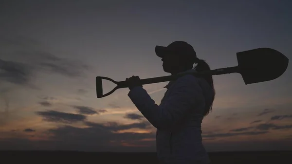 Silhouette of a senior farmer with a shovel at sunset, farming, small business of a gardener, the concept of an american work on plantation, an agronomist in a rural land of the land goes to dig soil — Stockfoto