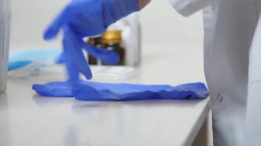 Hastane sağlık görevlisi ellerine tıbbi stiren eldivenler takar, koruyucu sağlık maskesi takar, hastanedeki hastaların sağlığını izler, beyaz önlüklü hemşire, sağlık araştırmaları, konsept eldiven modu.