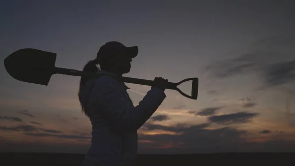 Silueta de un agricultor mayor con una pala al atardecer, la agricultura, la pequeña empresa de un jardinero, el concepto de un trabajo americano en la plantación, un agrónomo en una tierra rural de la tierra va a cavar suelo —  Fotos de Stock