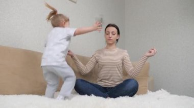 Kadın anne, koltukta otururken yoga yapıyor, mutlu aile, neşeli çocuk kız kanepeye zıplıyor, anne sağlıklı bir hayat sürüyor, güç toplamak için spor yapıyor, ev egzersizleri yapıyor.