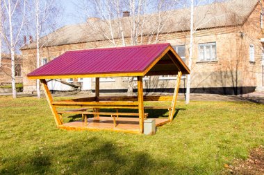 Ukrayna 'daki bir eğitim kurumunun avlusunda kırmızı çatılı ahşap bir çardak duruyor.