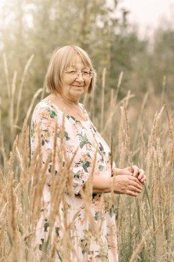 Dikenli uzun otların arasında yaşlı bir kadın. Sonbahar.