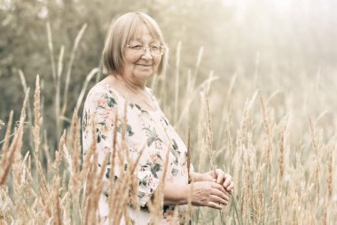 Dikenli uzun otların arasında yaşlı bir kadın. Sonbahar.