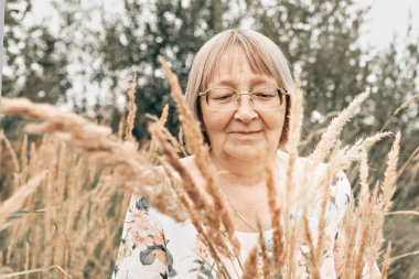 Dikenli uzun otların arasında yaşlı bir kadın. Sonbahar.