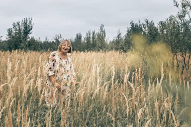 Dikenli uzun otların arasında yaşlı bir kadın. Sonbahar.