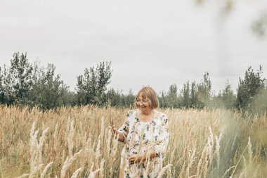 Dikenli uzun otların arasında yaşlı bir kadın. Sonbahar.