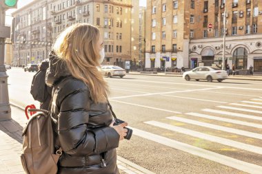 Şehir caddesinde yüzünde koruyucu maske takmış genç bir kadının portresi. Pandemik koronavirüs.