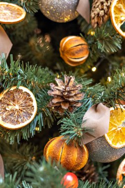 Noel ağacının arka planında koniler, mandalinalar ve portakallarla süslenmiş. Kış tatili Yeni Yıl