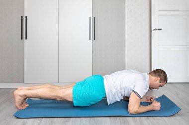 Güçlü, kaslı, evde antrenman yapan sağlıklı bir adam. Evde fitness var. Yoga.