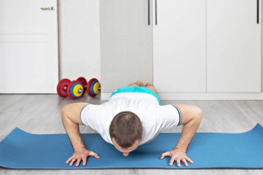 Güçlü, kaslı, kalas pozisyonunda antrenman yapan sağlıklı bir adam. Evde fitness