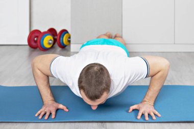 Güçlü, kaslı, kalas pozisyonunda antrenman yapan sağlıklı bir adam. Evde fitness