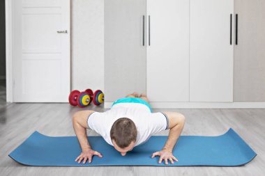 Güçlü, kaslı, kalas pozisyonunda antrenman yapan sağlıklı bir adam. Evde fitness