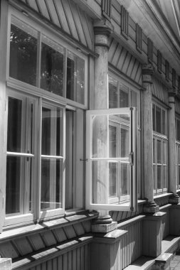 Eski ahşap bir binanın bir dizi kapalı penceresinin açık penceresi.