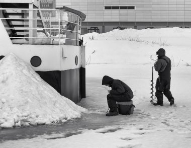 İki adam buzda buzda balık tutuyor. Hemen yanlarında bir tekne var ama dışarıda balık tutmayı tercih ediyorlar..