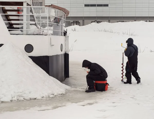 İki adam buzda buzda balık tutuyor. Hemen yanlarında bir tekne var ama dışarıda balık tutmayı tercih ediyorlar..