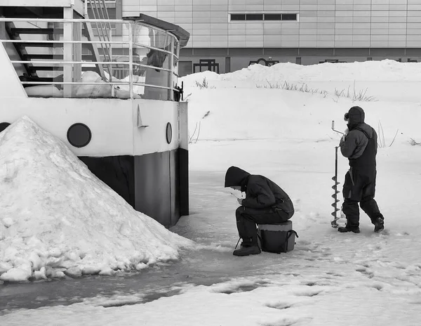 İki adam buzda buzda balık tutuyor. Hemen yanlarında bir tekne var ama dışarıda balık tutmayı tercih ediyorlar..