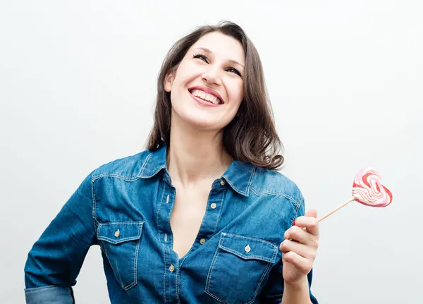 Attractive cheerful woman with candy in the form of heart — Stock Photo, Image