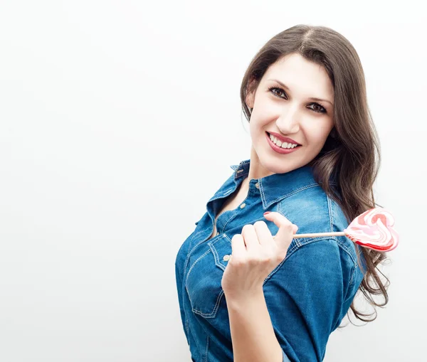 Attractive cheerful woman with candy in the form of heart — Stock Photo, Image