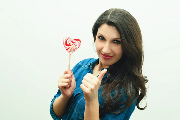 Attractive cheerful woman with candy in the form of heart — Stock Photo, Image