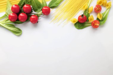 Geleneksel malzemeler spagetti makarnası. Akdeniz yemeği konsepti. Kurutulmuş makarna, fesleğen, domates. Beyaz arka plan. Kopyalama alanı olan üst görünüm
