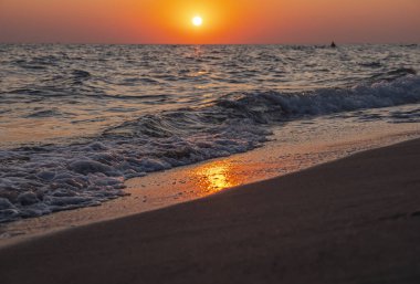 Denizin ve kumsalın üzerinde gün doğumu