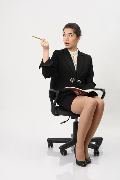 Donna d'affari seduta su una sedia e indicare una matita Immagini Stock Royalty Free
