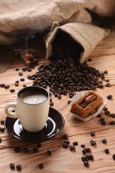 A hot cup of espresso with coffee beans and cinnamon on a wooden — Stock Photo, Image