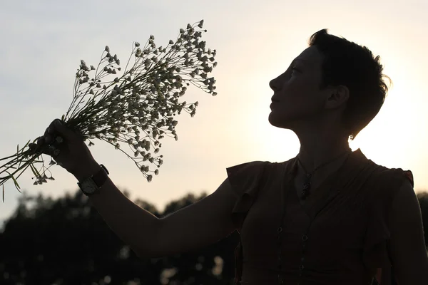 一个漂亮的女孩手捧鲜花的剪影 — 图库照片