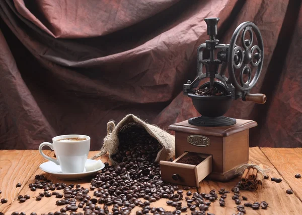 cup of coffee, coffee grinder, coffee beans in a sack