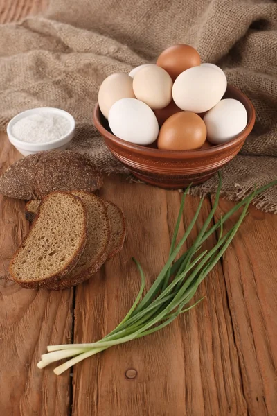 Raw eggs in an earthenware bowl, onions, bread, salt shaker — Stock Photo, Image