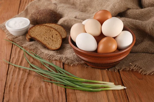 Ωμά αυγά σε ένα μπολ πήλινα, κρεμμύδια, ψωμί, αλατιέρα — Φωτογραφία Αρχείου