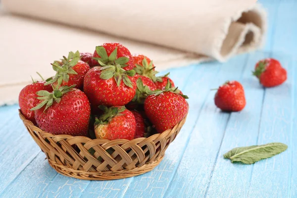 Strawberries in a wicker basket on a wooden boards painted — Stock Photo, Image