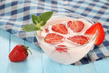 çilek ahşap tahta üzerinde bir cam kapta yoğurt ile