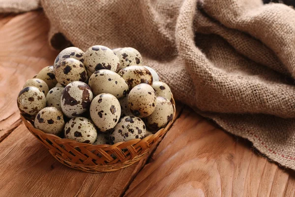 Huevos de codorniz en una canasta de mimbre en el fondo de tablones de madera — Foto de Stock