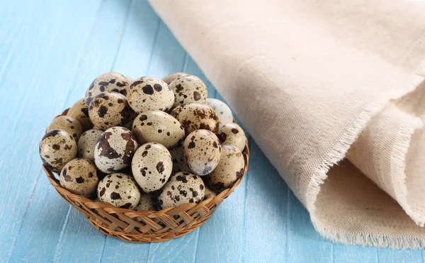 Huevos de codorniz en una canasta de mimbre sobre un fondo de madera — Foto de Stock