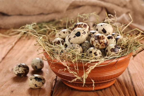 Huevos de codorniz en un tazón de barro con heno en el fondo de madera p — Foto de Stock