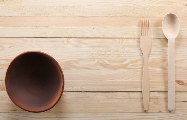 木汤匙和叉子在木板上的粘土碗上 — 图库照片