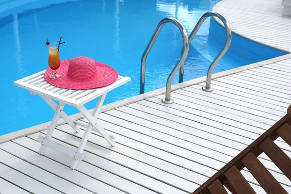 Cocktail com cereja em uma mesa de praia com um chapéu de palha perto — Fotografia de Stock