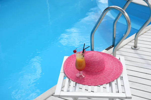 Cocktail com cereja em uma mesa de praia com um chapéu de palha perto — Fotografia de Stock