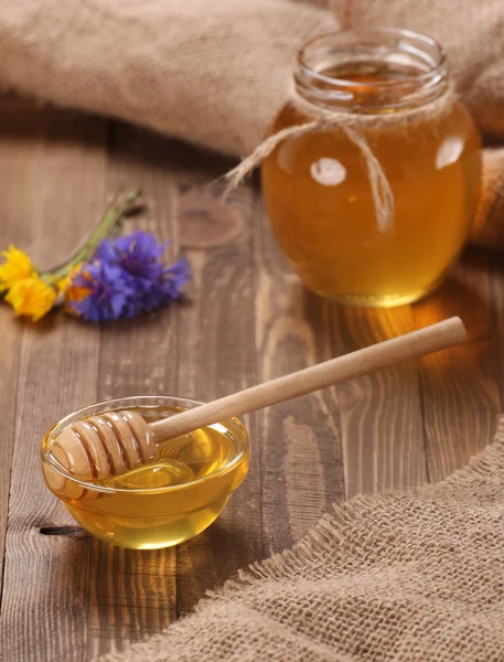 Honey in a glass bowl on a wooden boards background — Stock Photo, Image