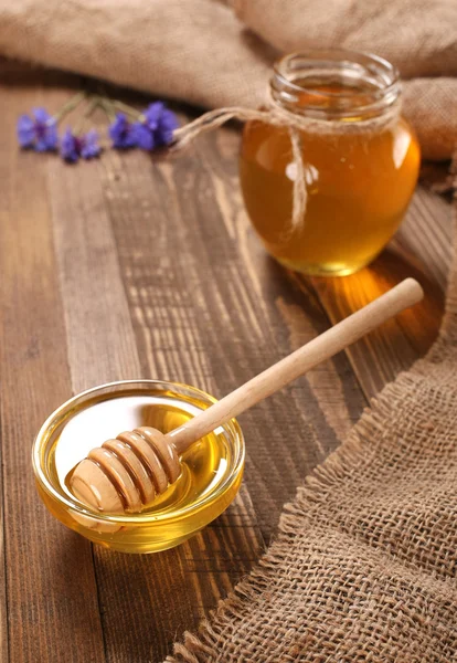 Miele in una ciotola di vetro su uno sfondo tavole di legno — Foto Stock