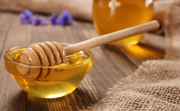 Honey in a glass bowl on a wooden boards background — Stock Photo, Image