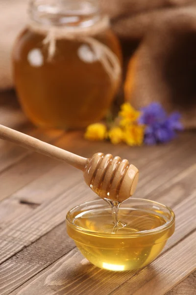 Honey in a glass bowl on a wooden boards background — Stock Photo, Image
